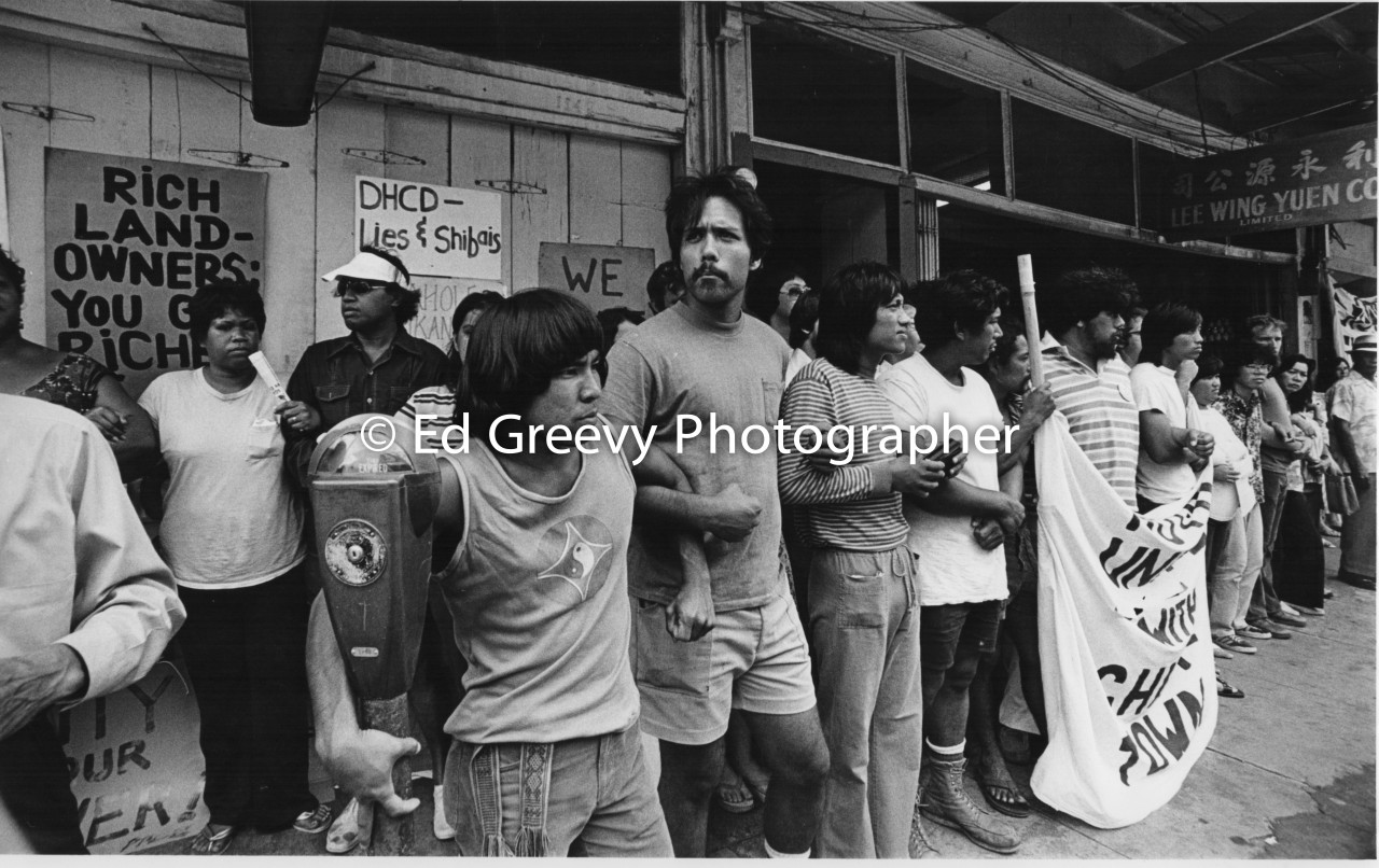 Pete Thompson (center) links arms with other anti eviction protesters at the Aloha Hotel in Chinatown. Alan Nakasone, Soli Niheu, Kalani Ohelo, Sandy Yee, and Justine Ferriera also pictured. (16 July 1977) Negative: 3073-4-28A | Ed Greevy Photographer